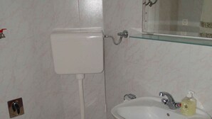 Ein Badezimmer mit Toilette, Waschbecken und einer roten Waschschüssel.