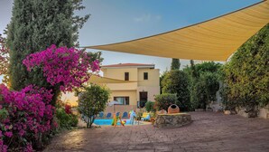 Une cour avec une piscine, des espaces de détente en plein air et un bâtiment doté d’un toit en tuiles.