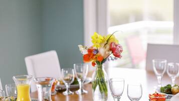 Una mesa de comedor dispuesta con diferentes platos, vasos y un jarrón de flores.