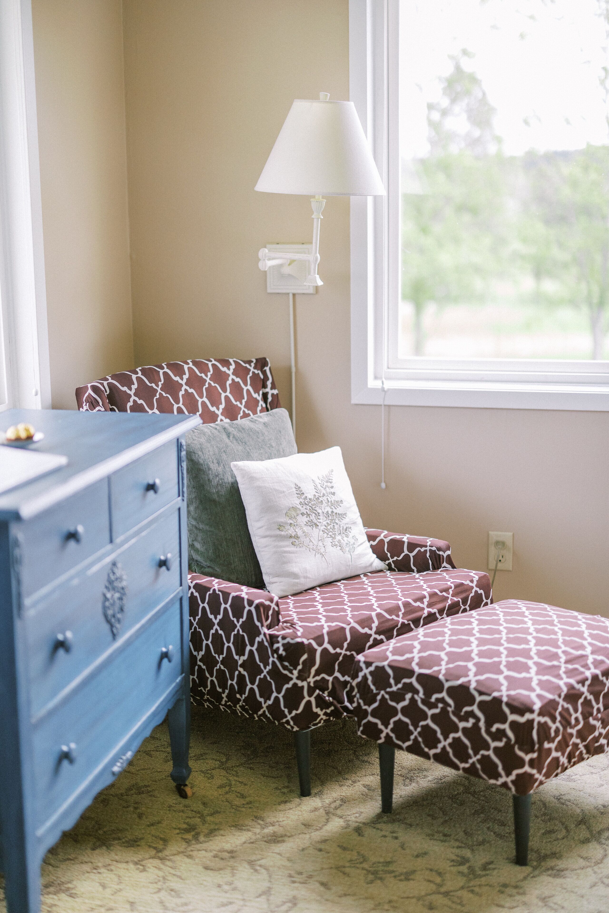A bedroom with a bed, a dresser, a lamp, and a window.