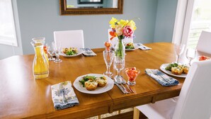 A dining table set with plates of food, glasses, and a vase of flowers.