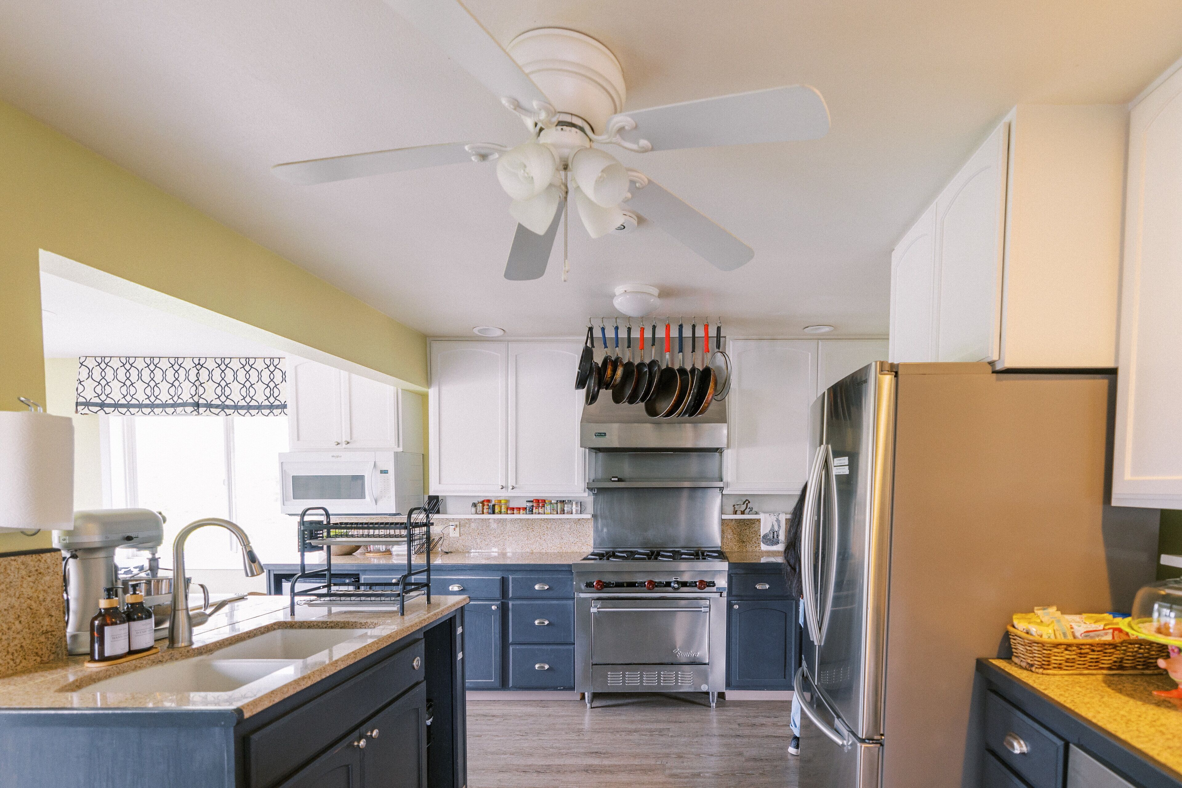 A modern kitchen with a central island, stainless steel appliances, and a ceiling fan.