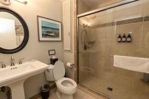 A bathroom with a toilet, sink, and shower.