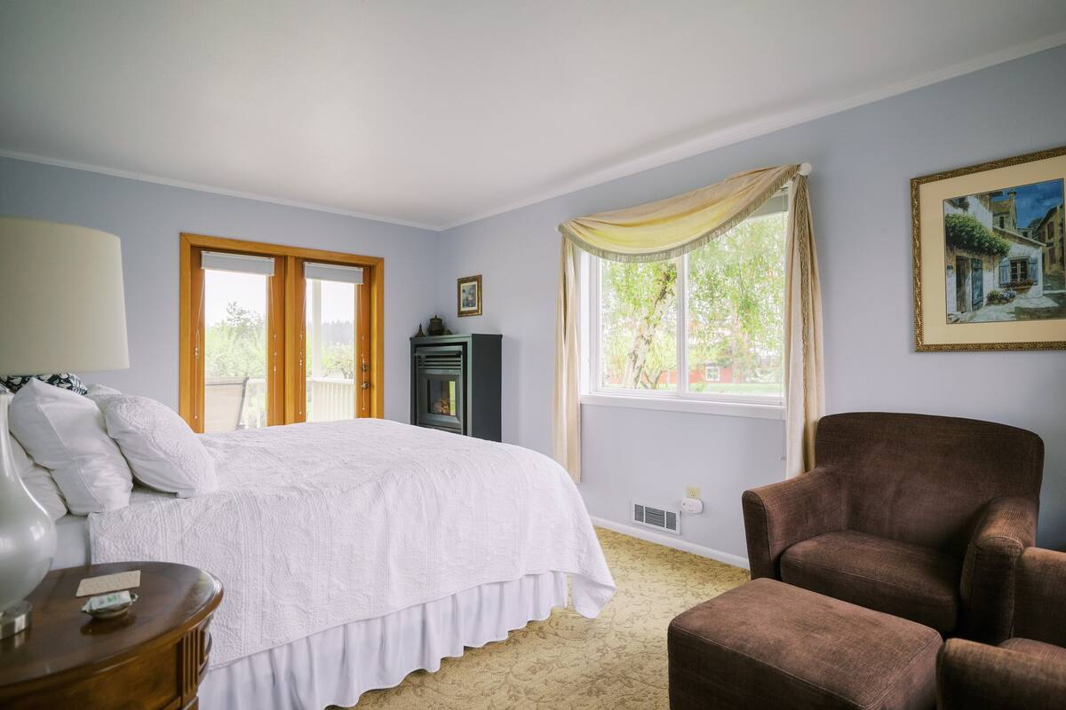 A bedroom with a bed, a chair, a lamp, and a window with curtains.