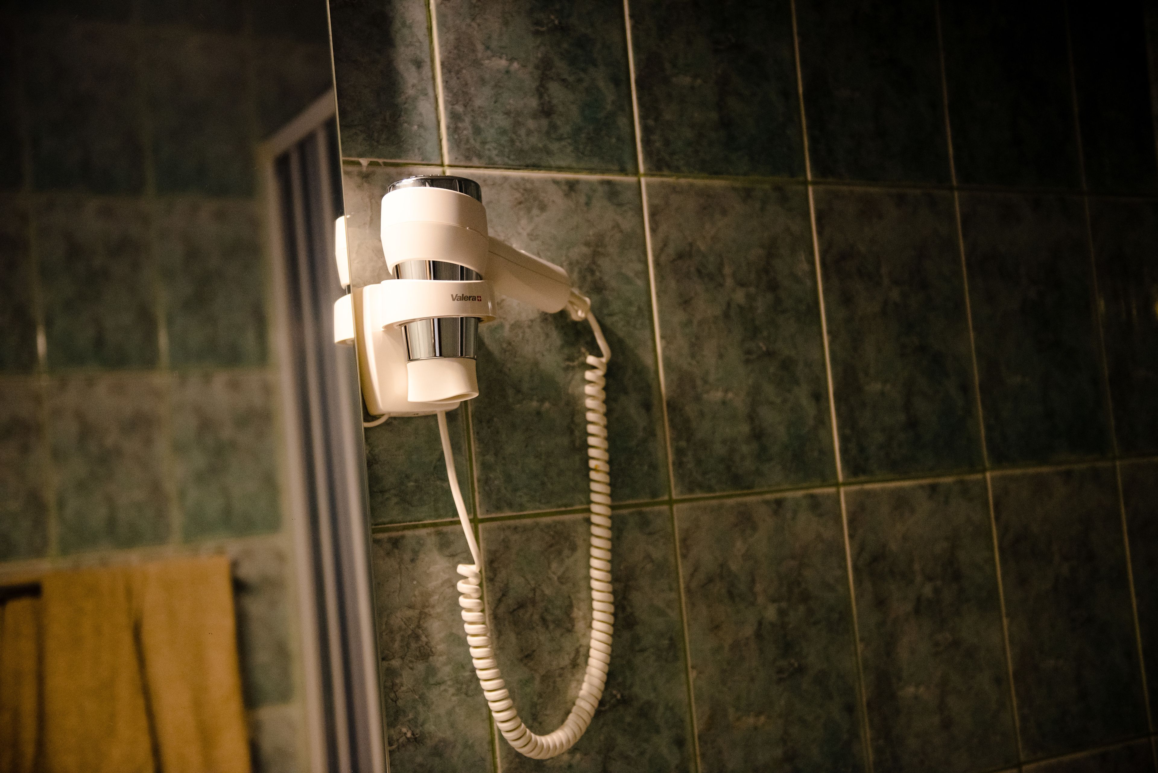 Ein Fön an einer gefliesten Wand in einem Badezimmer.