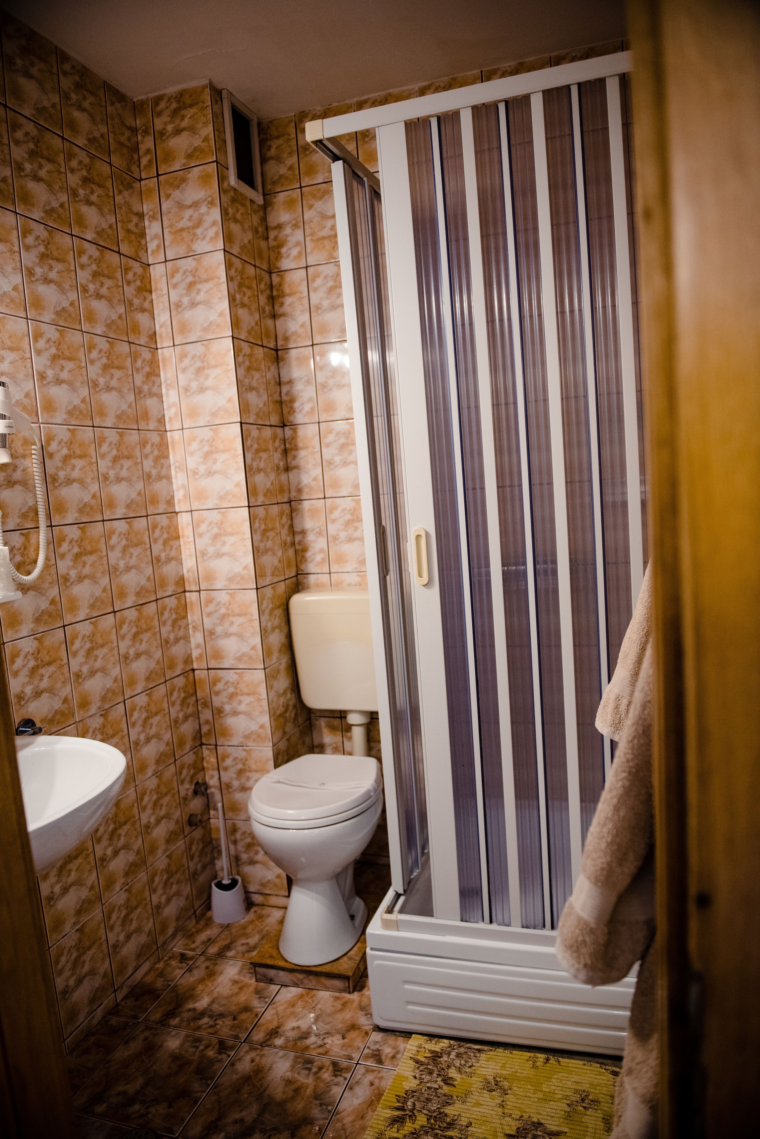 Un baño con inodoro, ducha con cortina, lavabo y un trapeador.