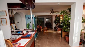 A reception area with a desk, chairs, and potted plants. - Pensiune Roua (Arad)