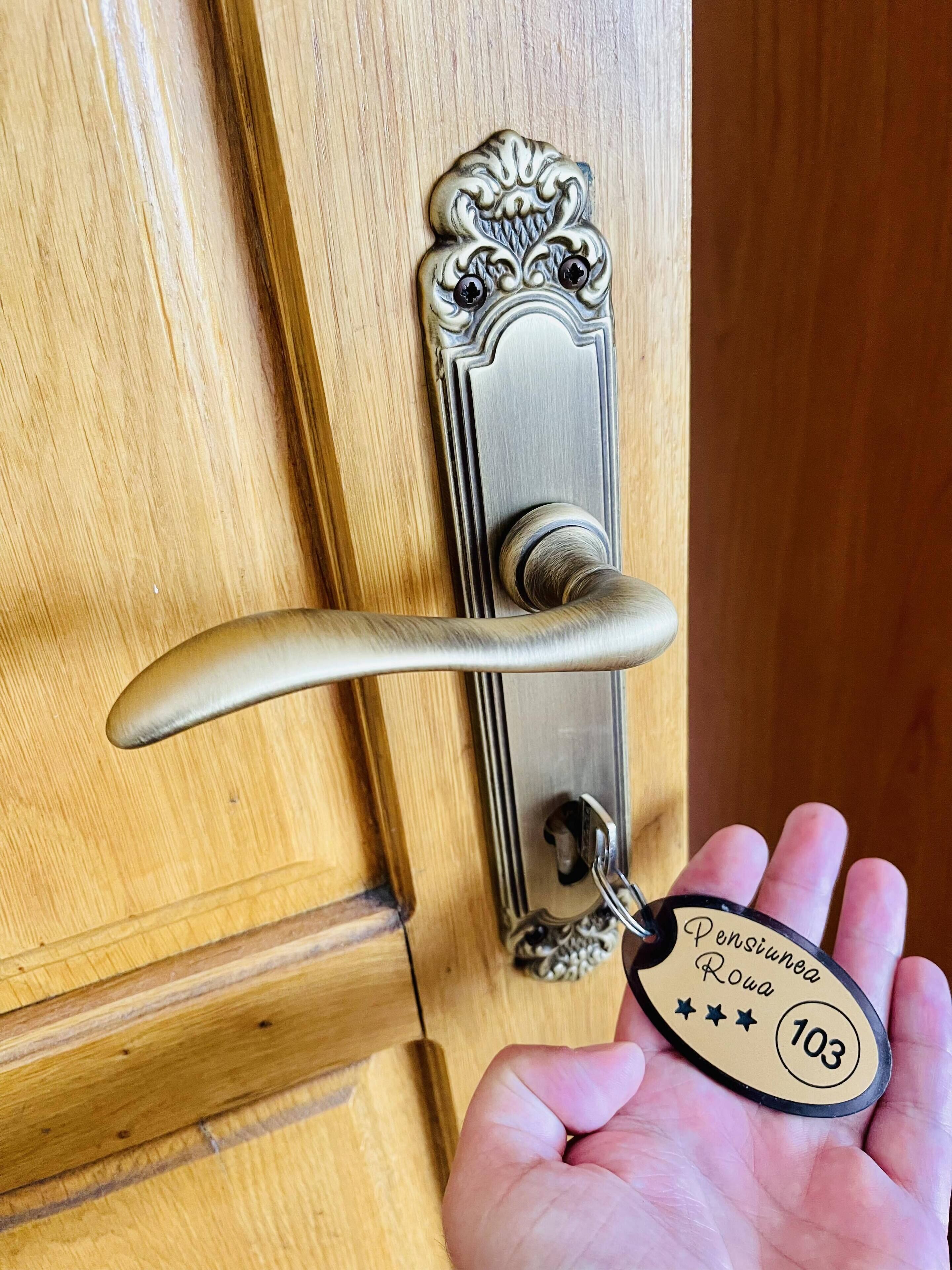 A wooden door with a brass handle and a keychain with the inscription "Pensiona Rowa 103".
