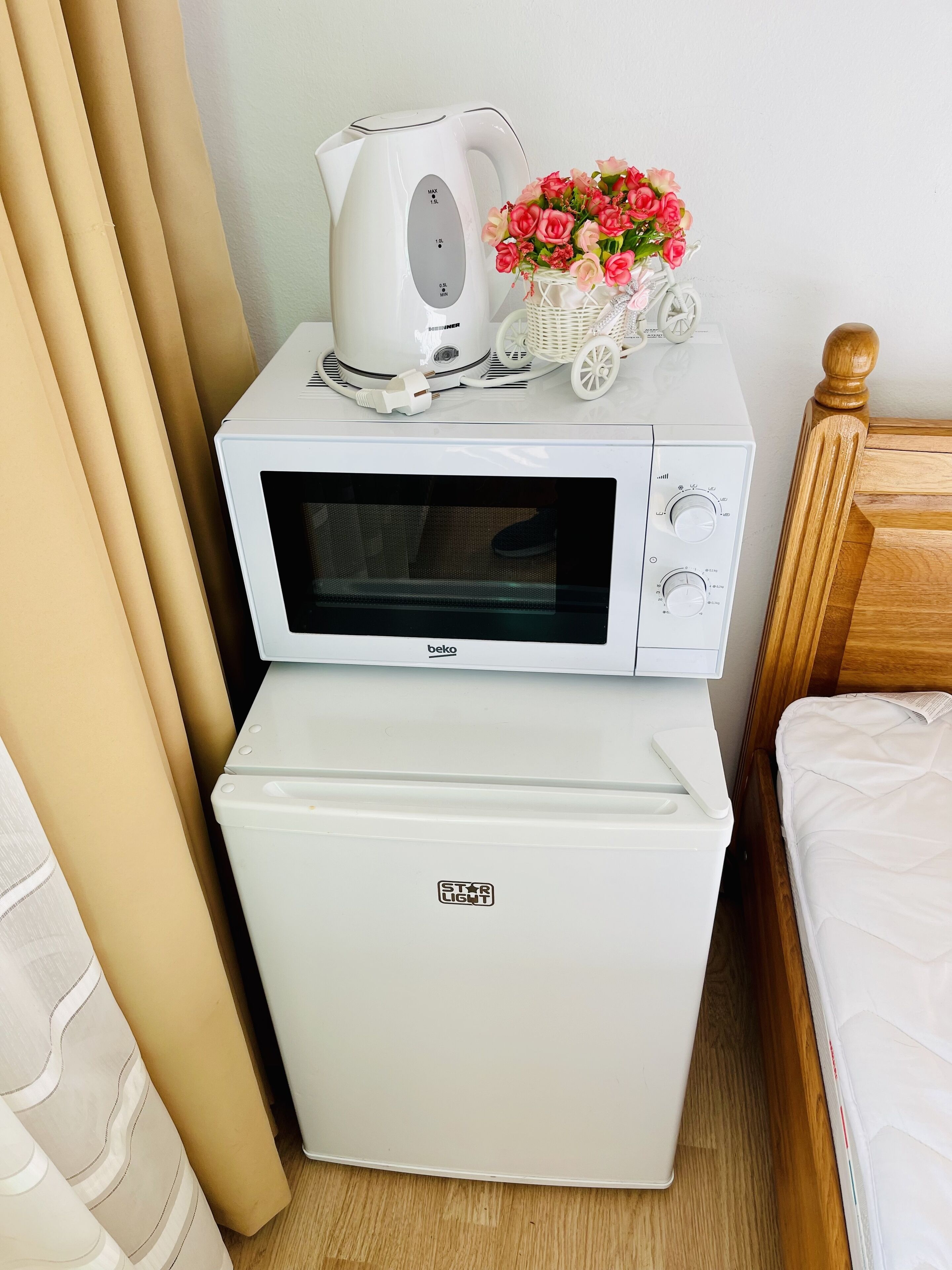 A kitchenette with a microwave, a small refrigerator, and a kettle.