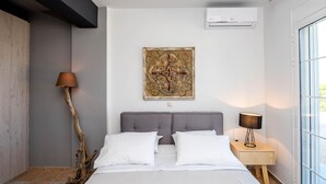 Un dormitorio con cama, dos mesitas de noche, aire acondicionado instalado en la pared y un ventanal grande.