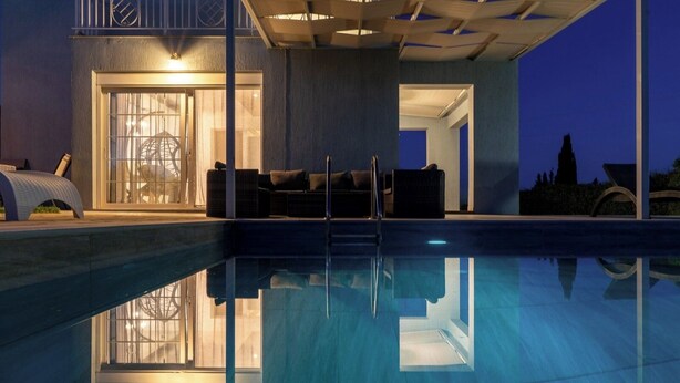 Un área de piscina moderna con agua cristalina, una zona de estar con asientos y un ventanal grande con vistas a la piscina.
