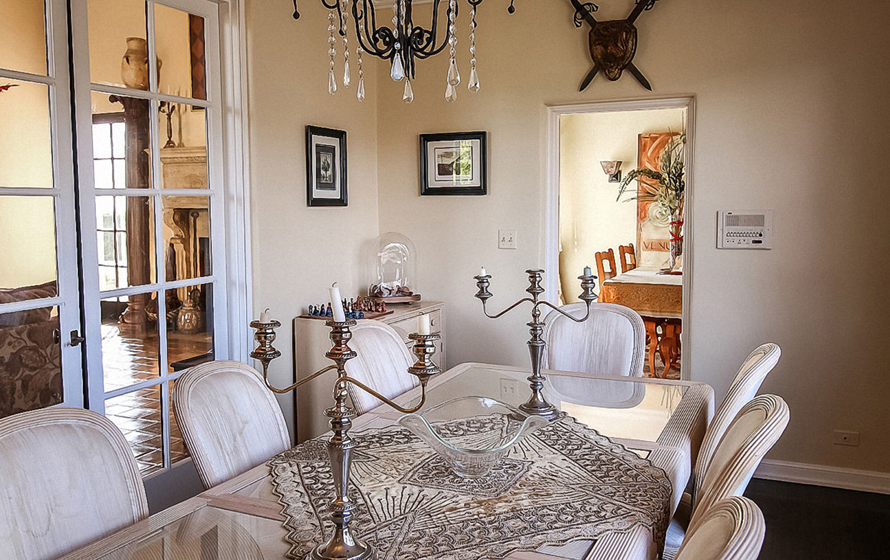 A dining area with a patterned tablecloth, ornate candelabras, and a chandelier.