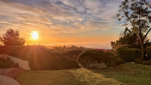 A sunset over a landscaped garden with a pathway and a building in the background.