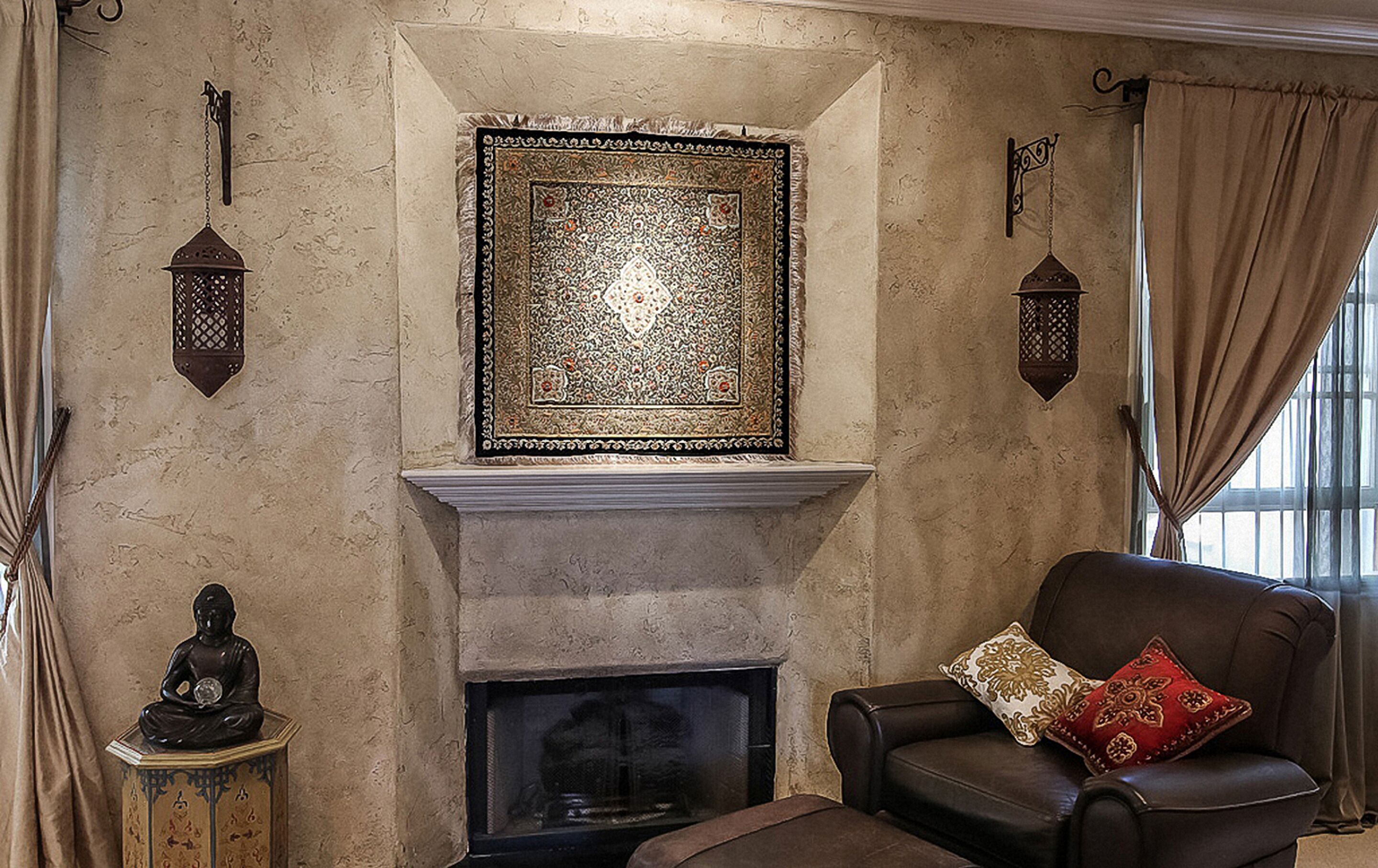 A living room with a fireplace, a Buddha statue, and a patterned rug.