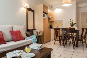 A modern living room with a sofa, a dining table with chairs, and a kitchen area with a microwave.