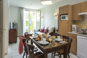 A dining area with a table set for breakfast, a sofa, and a kitchen with a microwave. - Apartment in Bergheim near Picturesque Town (Bergheim)
