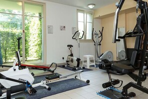 A gym with various exercise equipment, including a rowing machine, an elliptical, and a weight bench.