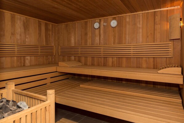 A sauna room with wooden benches and a stone bench.