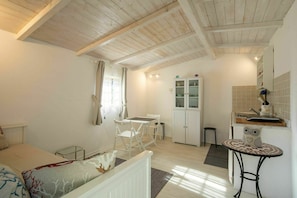 A cozy room with a bed, a small table, a chair, a cabinet, and a kitchenette area. - House & Dependance for 6 People, Wonderful place, Garden, Wifi, Tuscany (Corsanico-bargecchia)