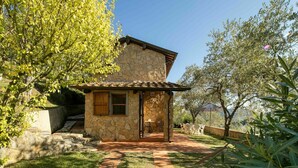 Une maison en pierre avec un toit en tuiles, un petit porche et un chemin menant à une table et à des chaises.