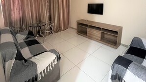 Ein modernes Wohnzimmer mit einer Couch, einem Couchtisch, einem Fernseher und einem TV-Schrank.