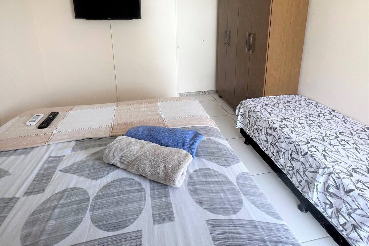 Une chambre à coucher comprenant un lit, une armoire et un téléviseur fixé au mur.