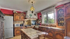 A kitchen with wooden cabinets, a dining table, a microwave, and a window.