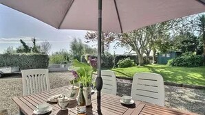 An outdoor dining area with a table, chairs, and an umbrella.