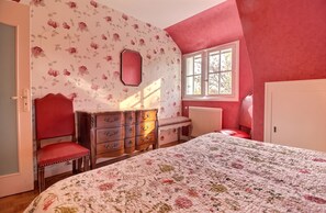 A bedroom with a bed, a dresser, a chair, a window, and a door.