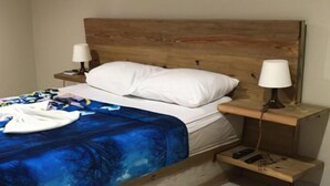 A bed with a wooden headboard, white pillows, and a blue blanket. There are two bedside tables with lamps. - El Currican (Guayacanes)