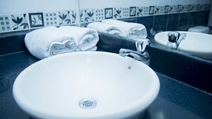 Un lavamanos con espejo, un perchero con toallas dobladas y un salpicadero de azulejos.