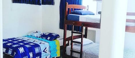 Un dormitorio con literas, una cama individual y un ventanal con cortinas.