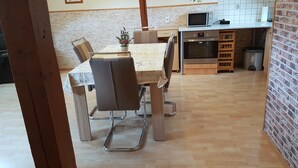 Ein Essbereich mit Tisch und Stühlen, eine Küche mit Mikrowelle und Backofen sowie dekorative Teller an der Wand.