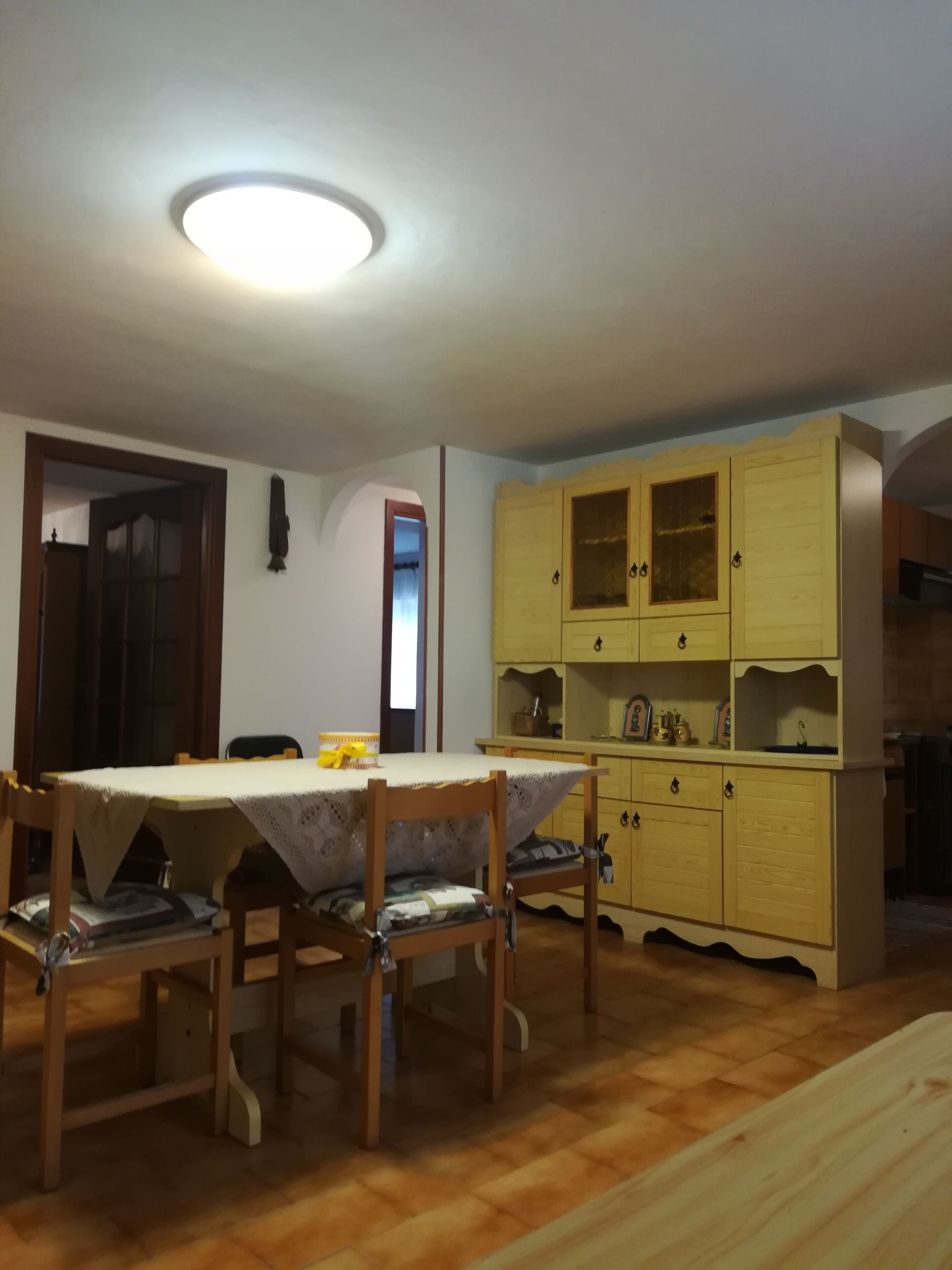 A dining area with a table and chairs, wooden cabinets, and a ceiling light.