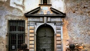 Un edificio desgastado por el tiempo con un arco central, flanqueado por dos columnas de piedra con capiteles esféricos.