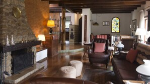 Una sala de estar acogedora con chimenea, mobiliario de cuero y una ventana de vitral.