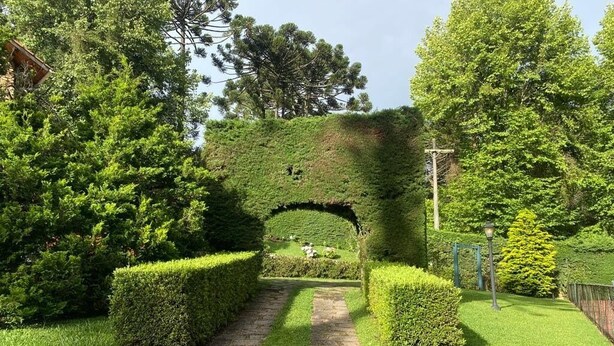 Un sendero de piedra que atraviesa un jardín cuidado, con un arco de seto.