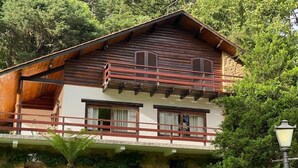 Una cabaña de madera con balcón, base de piedra y césped cuidado.