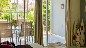 A room with a bed, a sliding glass door to an outdoor area, a table with chairs, and decorative vases.