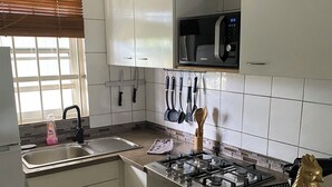A kitchen with white cabinets, a stainless steel sink, a gas stove, and a microwave.