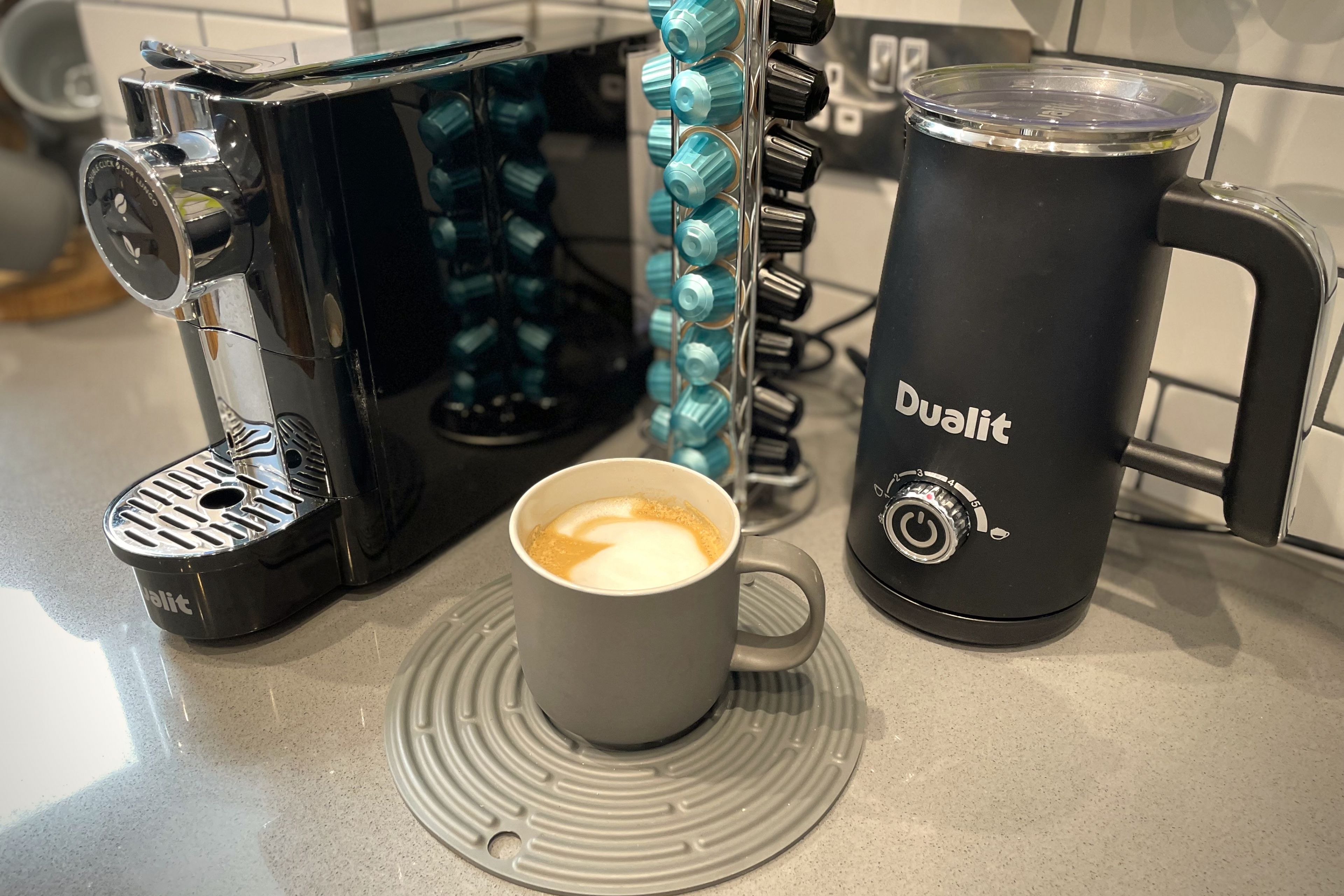 Eine Kaffeemaschine, eine Kaffeetasse und ein Wasserkrug auf einer Küchenarbeitsplatte.