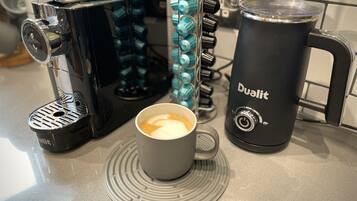 Eine Kaffeemaschine, eine Kaffeetasse und ein Wasserkrug auf einer Küchenarbeitsplatte.