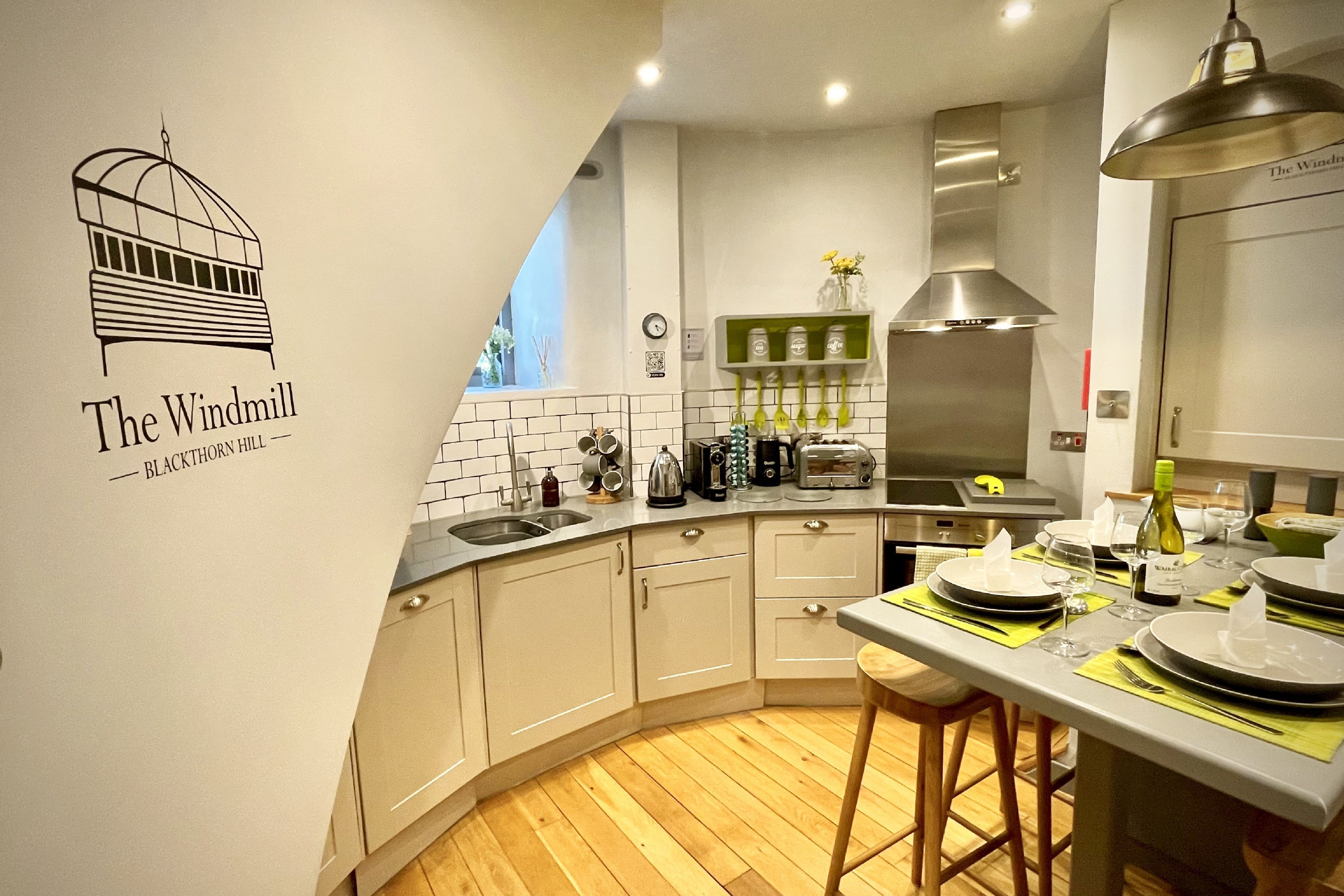 A modern kitchen with a curved countertop, stainless steel appliances, and a wall-mounted coffee machine.