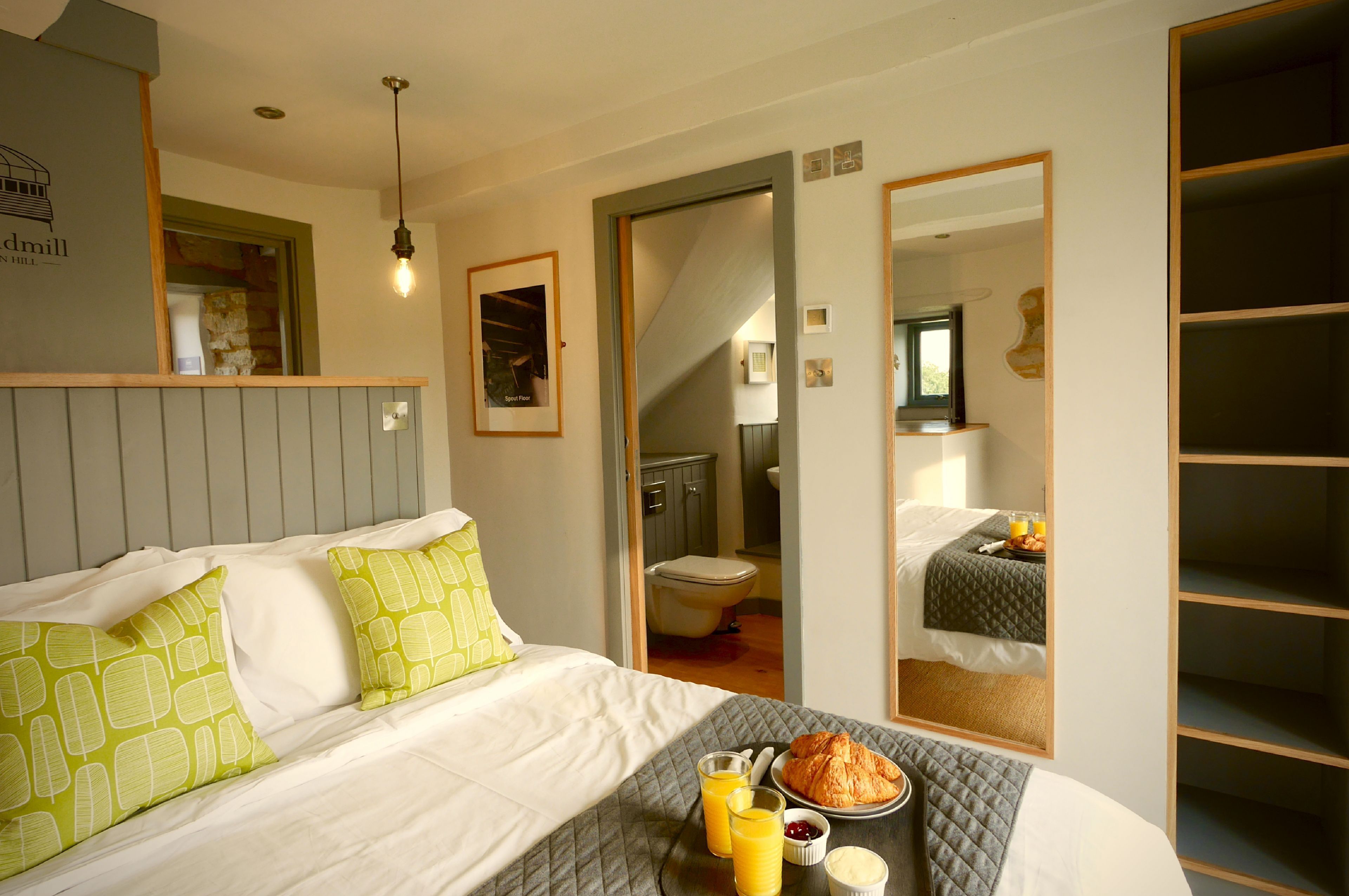 A hotel room with a bed, a breakfast tray, and a bathroom visible through an open door.