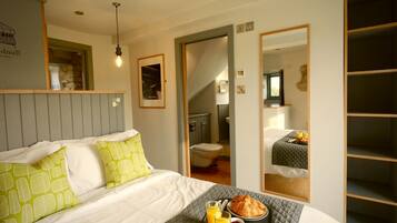 A hotel room with a bed, a breakfast tray, and a bathroom visible through an open door.