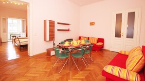 Un coin repas avec une table dressée pour quatre personnes, entourée de chaises vertes.
