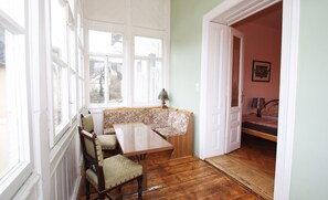 A room with a wooden bench, a table, and a door leading to another room. - Raisa big 2 ci. Apartment with large terrace and kitchen (Pressbaum)