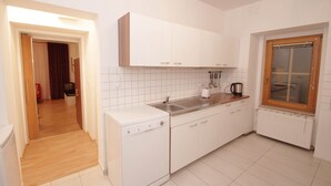 A kitchen with white cabinets, a dishwasher, a sink, and a window with a wooden frame.