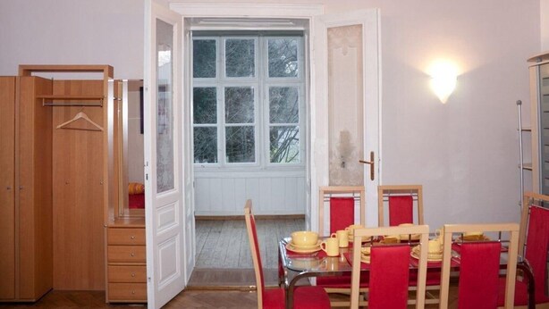 A room with a dining table set for four, a wooden wardrobe, and a door leading to a balcony. - Raisa Superior Apartment with 2 bedrooms, 2 terraces and marble bathroom  (Pressbaum)