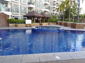 A swimming pool with a gazebo, surrounded by a brick wall and greenery. - CF10C The Parkside Villas, Family room with kichen, dining,living area & balcony (Pasay)